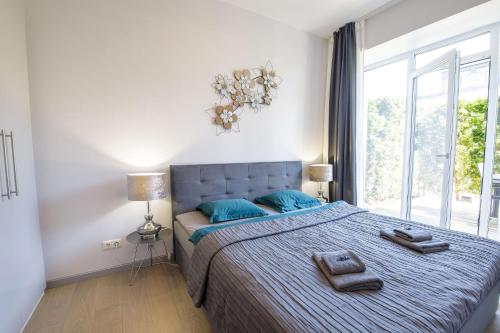a bedroom with a bed with blue pillows and a window at New apartment LOFT MAJORI with terrace in Jūrmala