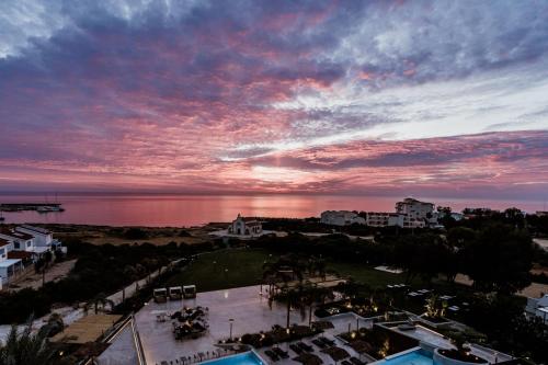 een uitzicht op een zonsondergang boven een stad met de oceaan bij Cavo Zoe Seaside Hotel in Protaras