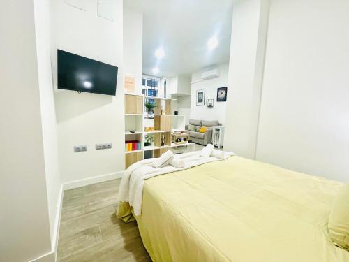 ein weißes Schlafzimmer mit einem Bett und einem Flachbild-TV in der Unterkunft Cómodo, moderno y bien situado P3 in Málaga