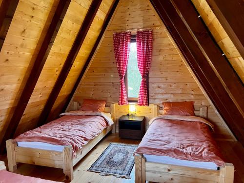 two beds in a log cabin with a window at Etno Idila D&D in Žabljak