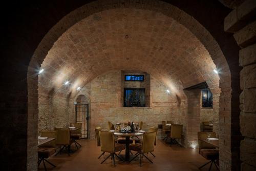 a dining room with tables and chairs and a brick wall at Precise Tale Poggio Alla Sala in Montepulciano