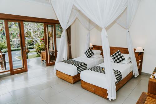 two beds in a room with windows at Villa Capung Mas Ubud in Ubud