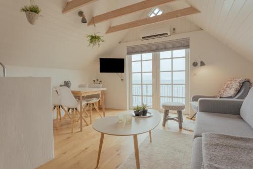 a living room with a couch and a table at Unique boathouse by the foreshore / Sea view in Strendur