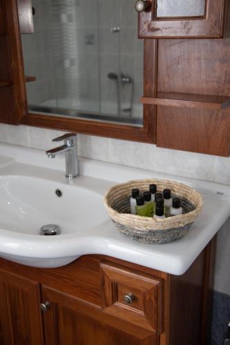 a bathroom sink with a basket of bottles on it at Mylos House with sea view in Lixouri