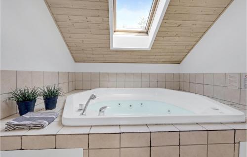 a bath tub in a bathroom with a skylight at Beautiful Home In Vggerlse With 4 Bedrooms, Sauna And Wifi in Bøtø By