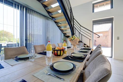 a dining room with a table and chairs and a staircase at Un nid dans la Grange - Maison avec jacuzzi et sauna in Boué