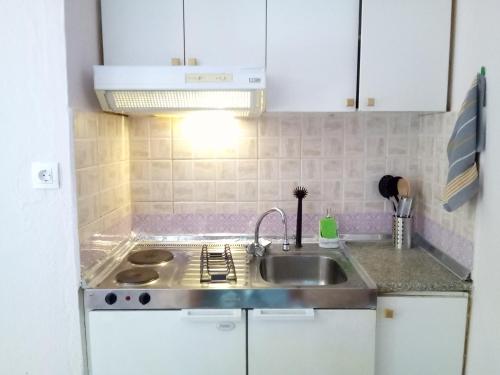 a kitchen with white cabinets and a sink at Studios Thomas in Limenaria