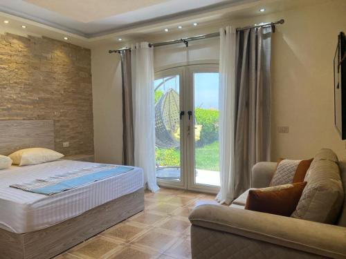 a bedroom with a bed and a couch and a window at Villa Front Beach First row family only in Ain Sokhna