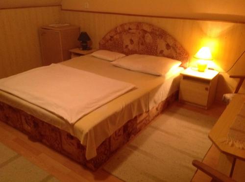 a bedroom with a large bed with a wooden headboard at Club Torony Hotel in Torony