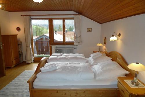 a bedroom with a bed with white sheets and a window at Haus Schmidberger in Schneizlreuth