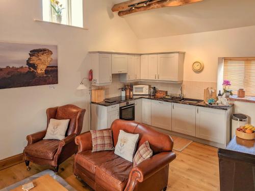 a living room with two chairs and a kitchen at Cruck in Sinnington