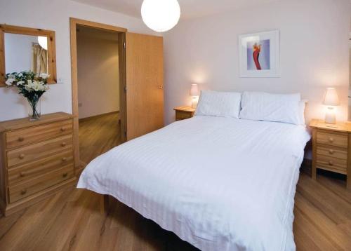 a bedroom with a large white bed and two night stands at Red Rock Apartments in Dawlish