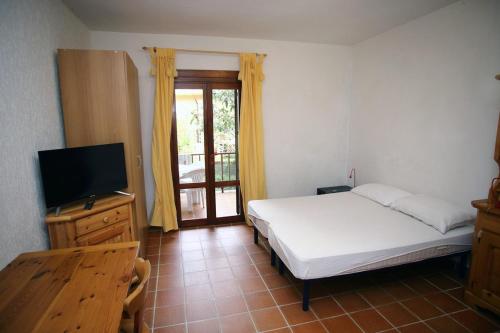 a bedroom with a bed and a flat screen tv at Dimore Dell'Isola Rossa in Isola Rossa