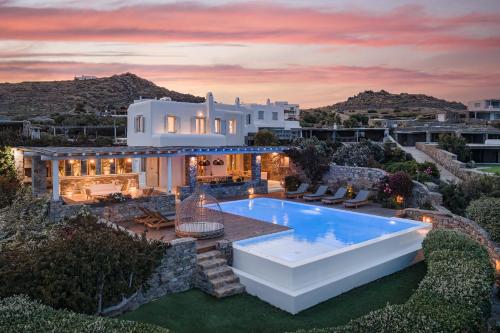 a villa with a swimming pool at dusk at El Sueno Villa Mykonos in Kalafatis
