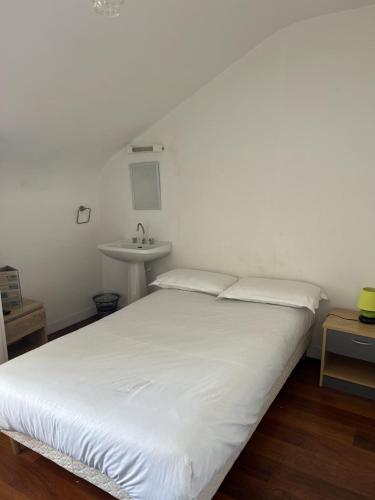 Cette chambre comprend un lit blanc et un lavabo. dans l'établissement Chez Marco, à La Gouesnière