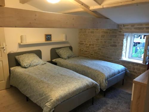 1 Schlafzimmer mit 2 Betten und Ziegelwand in der Unterkunft L Abricotier in Saint-Crépin