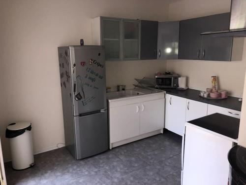 eine Küche mit einem Edelstahlkühlschrank und weißen Schränken in der Unterkunft T2 LA CIOTAT 60M2 AVEC TERRASSE EQUIPÉE in La Ciotat