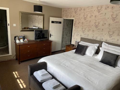 a bedroom with a large white bed and a television at The Swan Inn in Monks Eleigh