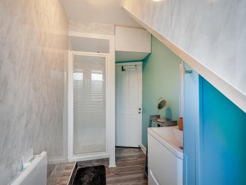 uma casa de banho com um lavatório branco e uma parede azul em Millport Bay View em Millport