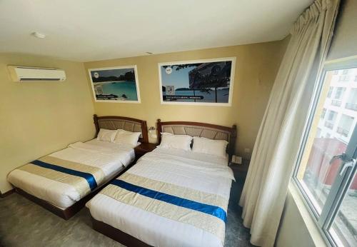 two beds in a hotel room with a window at Aladdin Dream Hotel in Johor Bahru