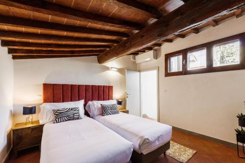 Duas camas num quarto com tectos e janelas em madeira em Apartments Florence- Faenza Terrace em Florença