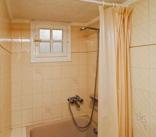 a bathroom with a tub and a shower with a window at Villa Aristea in Kalo Chorio