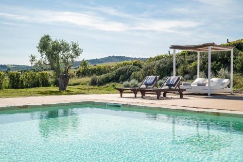 two chairs and a bench next to a swimming pool at Locanda Fontelupa in Campagnatico