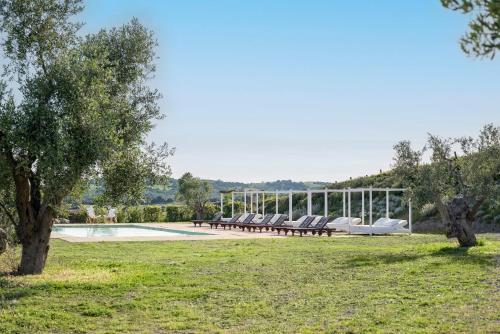 a pool with lounge chairs in a field with trees at Locanda Fontelupa in Campagnatico