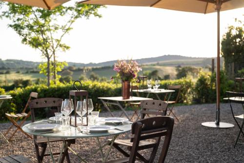 CampagnaticoにあるLocanda Fontelupaのワイングラス付きテーブル、傘下の椅子