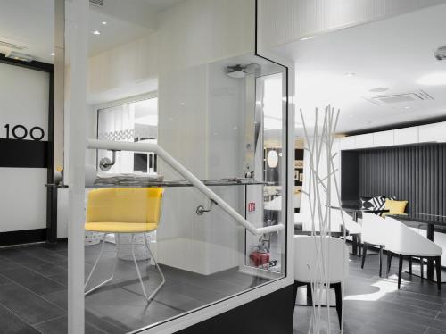 a kitchen with a yellow chair and a dining room at Hotel Ekta Champs Elysées in Paris