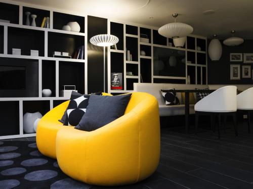 a yellow chair in a living room with black walls at Hotel Ekta Champs Elysées in Paris