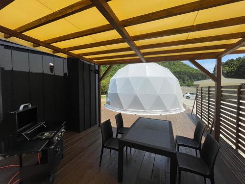 a patio with a table and chairs and a white ceiling at Ｋ&Ｂグランピング　天空の城 in Takeda