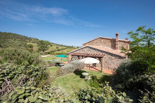 an external view of a stone house with an umbrella at Locanda Fontelupa in Campagnatico