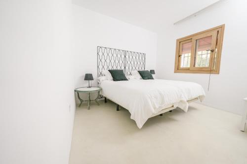 Un dormitorio blanco con una cama grande y una ventana en Moott Homes Suites Villa Costacabana en Almería