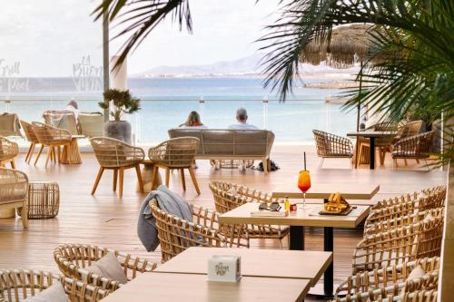 a restaurant with tables and chairs and a view of the ocean at Arrecife Gran Hotel & Spa in Arrecife