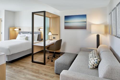 a hotel room with a bed and a couch and a desk at SpringHill Suites by Marriott Jacksonville Beach Oceanfront in Jacksonville Beach