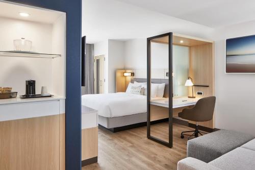 SpringHill Suites by Marriott Jacksonville Beach Oceanfront في شاطئ جاكسونفيل: غرفة في الفندق مع سرير ومكتب