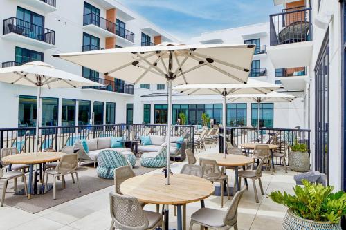 an outdoor patio with tables and chairs and umbrellas at SpringHill Suites by Marriott Jacksonville Beach Oceanfront in Jacksonville Beach