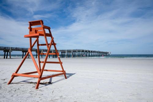 an orange lifeguard chair on the beach with a pier at SpringHill Suites by Marriott Jacksonville Beach Oceanfront in Jacksonville Beach