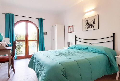 a bedroom with a bed with a green comforter and a window at Borgo de' Muracci in Ribolla