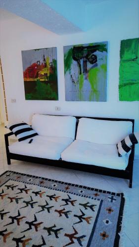 a white couch in a room with paintings on the wall at Residenza Bertolini in Fosdinovo