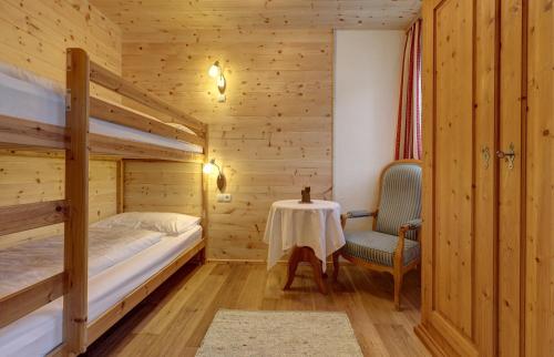 a bedroom with two bunk beds and a table and a chair at Schüsslerhof in Campo Tures