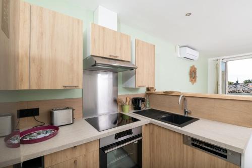 a kitchen with wooden cabinets and a sink and a stove at Emplacement idéal au cœur de Sanary sur le port vue mer in Sanary-sur-Mer