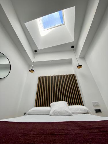 a white bedroom with a bed with a window at Evenia Alcalá Boutique Hotel in Alcalá de Henares