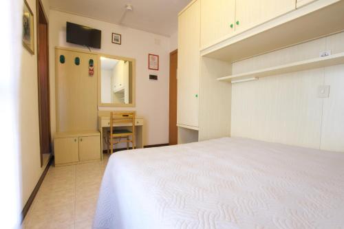 Schlafzimmer mit einem weißen Bett und einem Schreibtisch in der Unterkunft Residence Madrid Stanza in Lido di Jesolo