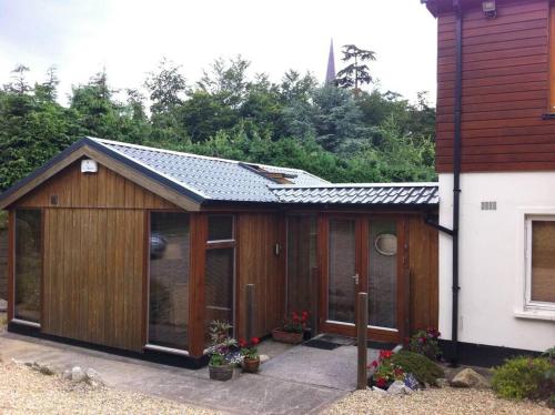 a large wooden building with glass windows next to a house at Self catering apartment at Beechwalk House. in Enniskerry