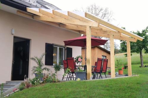 a pergola with chairs and a table with an umbrella at Ferienhaus Käfer in Steinbach