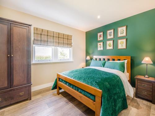 a green bedroom with a bed and a window at Auld Acquaintance Cottage in Dalswinton