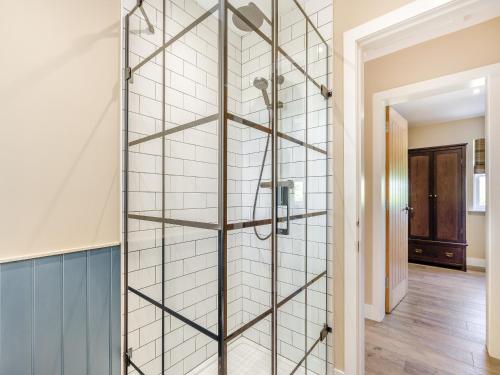 a glass shower wall with a shelf in a bathroom at Auld Acquaintance Cottage in Dalswinton