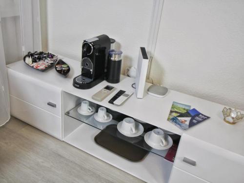 a white cabinet with a coffee maker and cups on it at Ferien am Luganer See mit Seesicht in Bissone